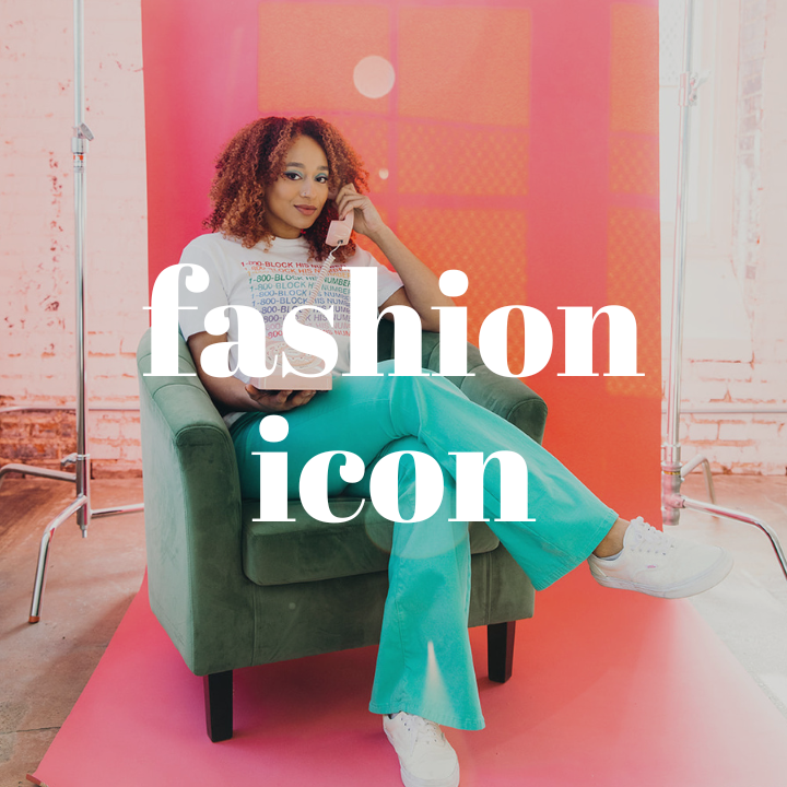 Woman with red curly hair sitting in a green velvet chair while talking on a pink rotary phone. She is wearing a white graphic tee, teal flare jeans, and white sneakers. The words "Fashion Icon" are displayed in the center of the photo.
