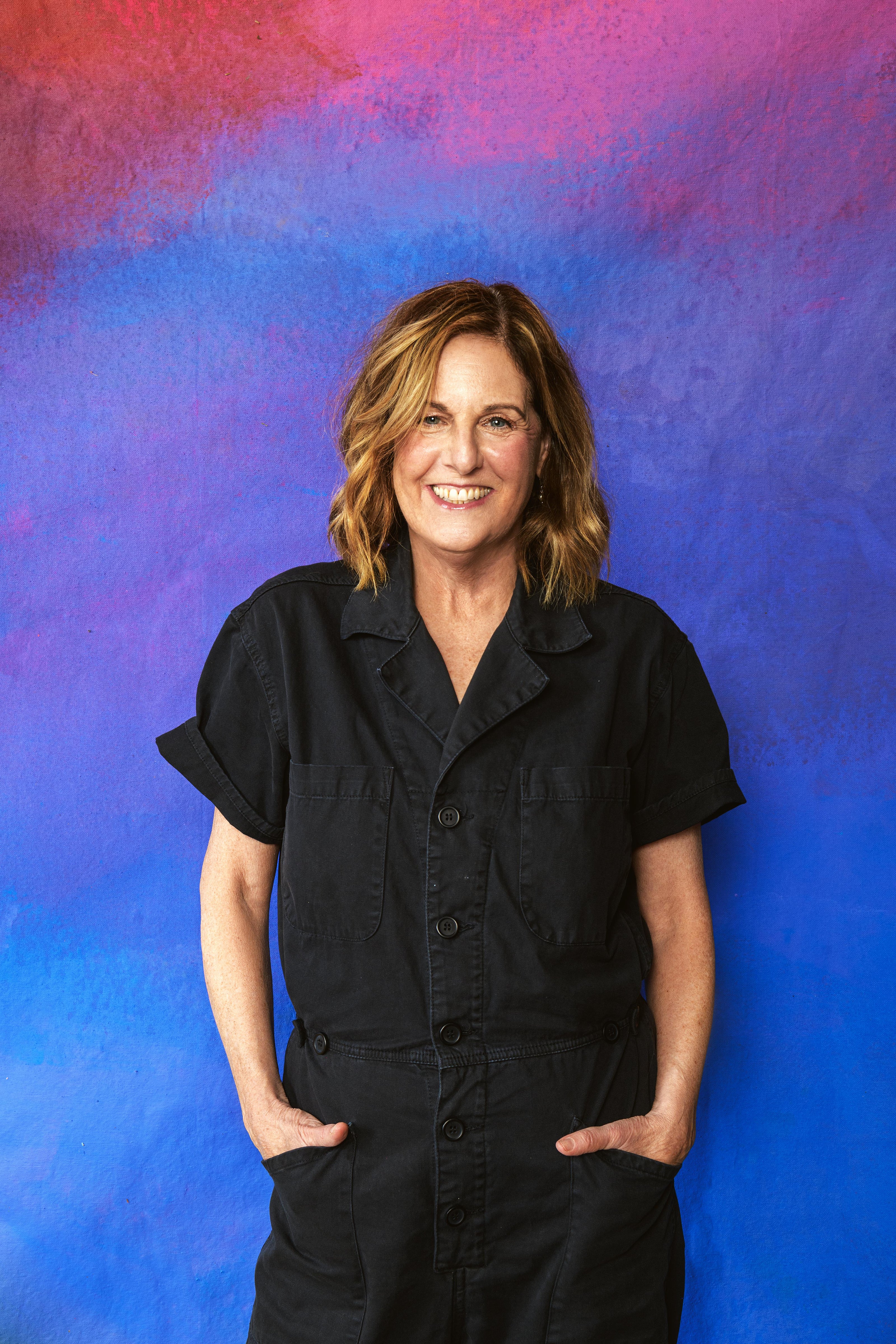 Person wearing a black outfit against a colorful abstract background