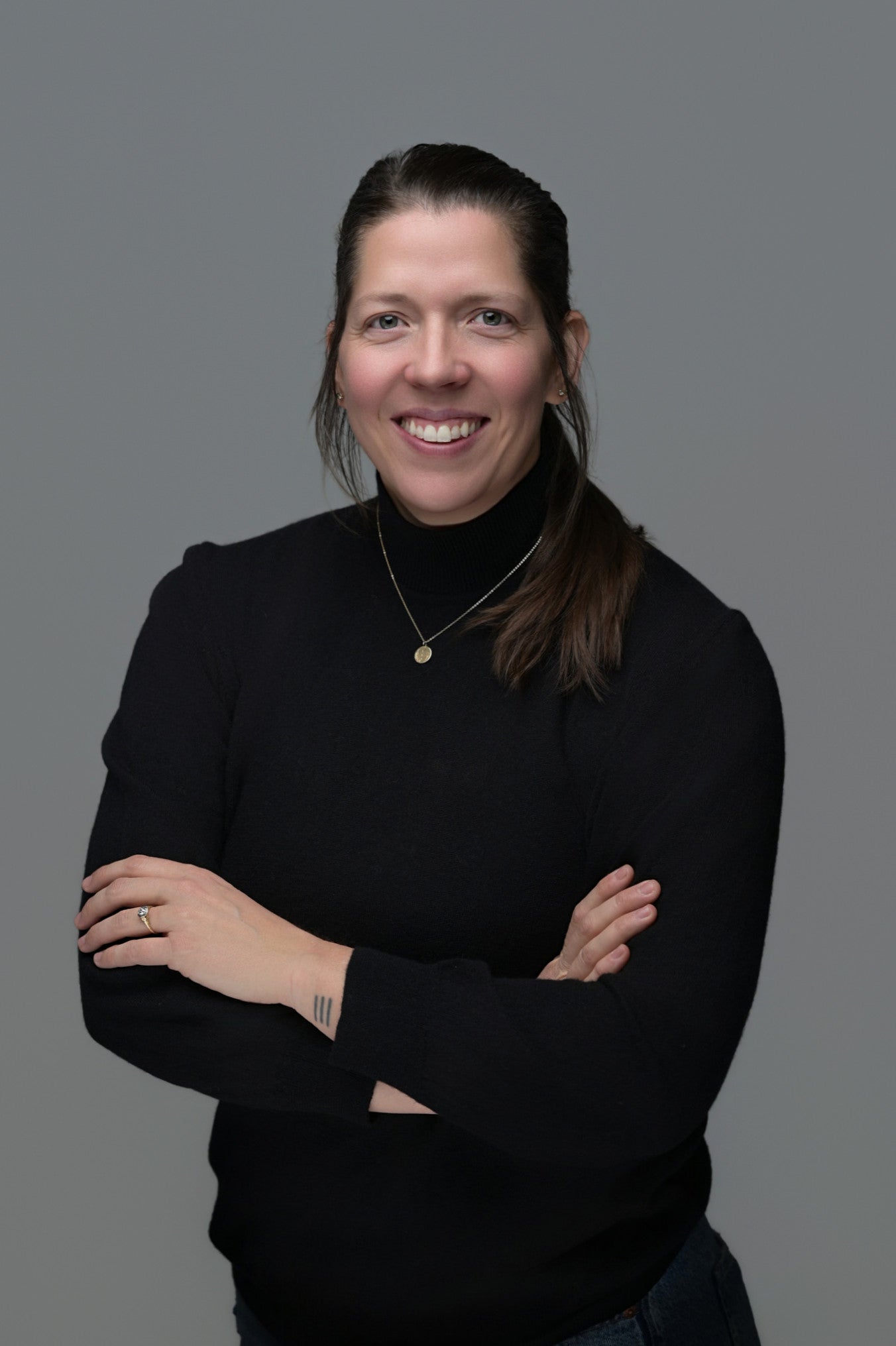 Person wearing a black sweater against a gray background