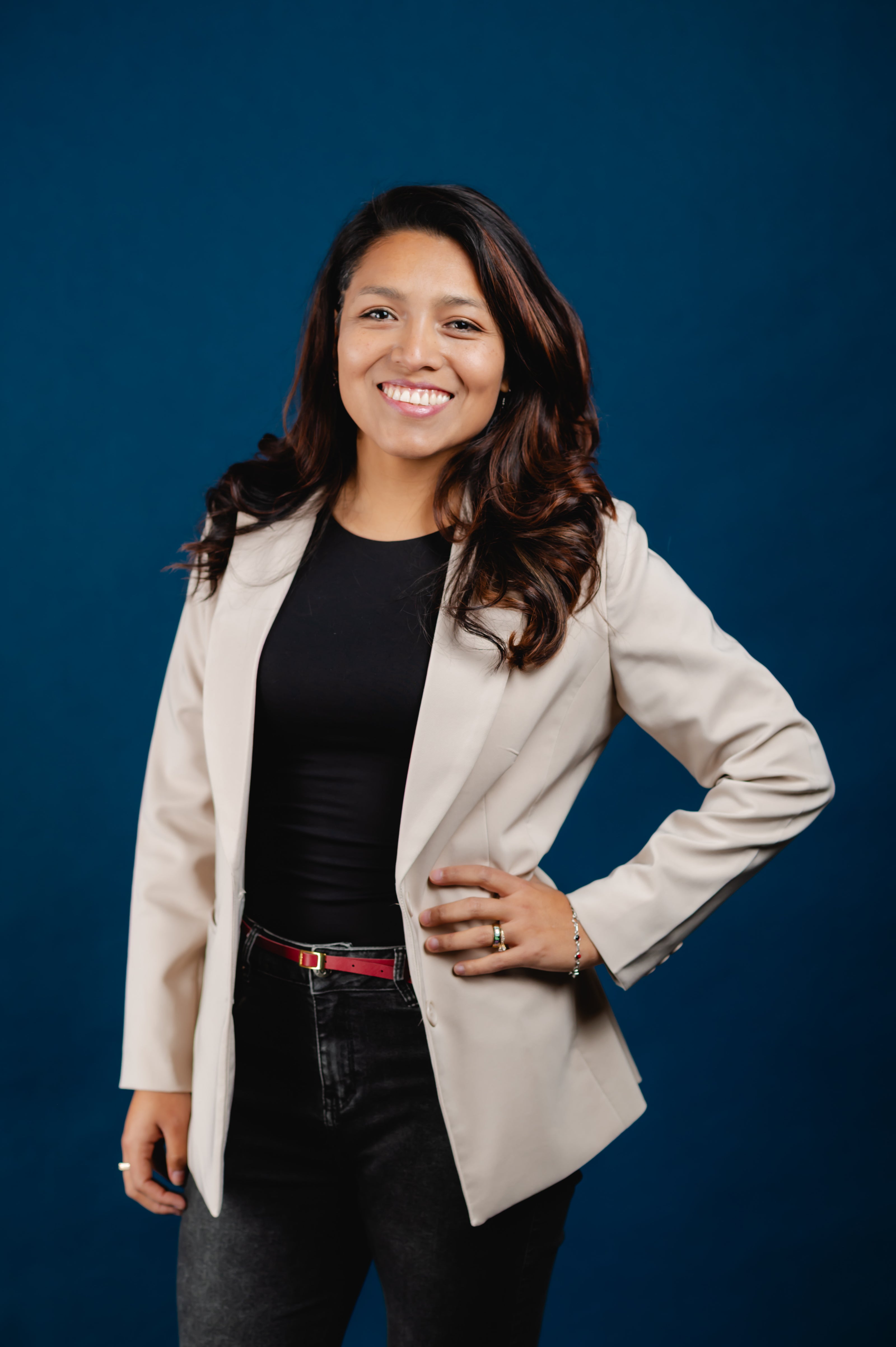 Woman wearing a beige blazer over a black top against a blue background