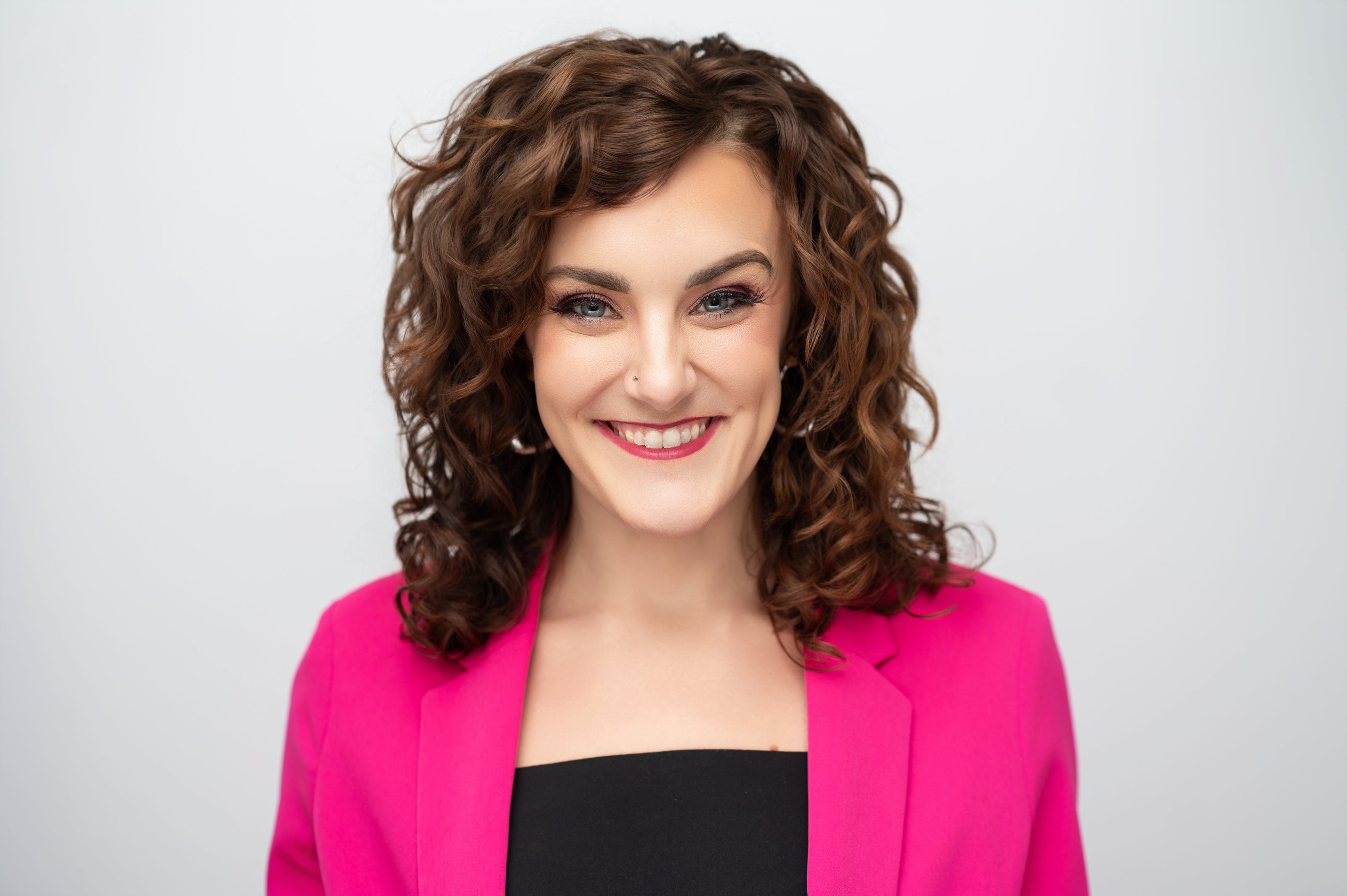 Woman wearing a bright pink blazer against a light gray background