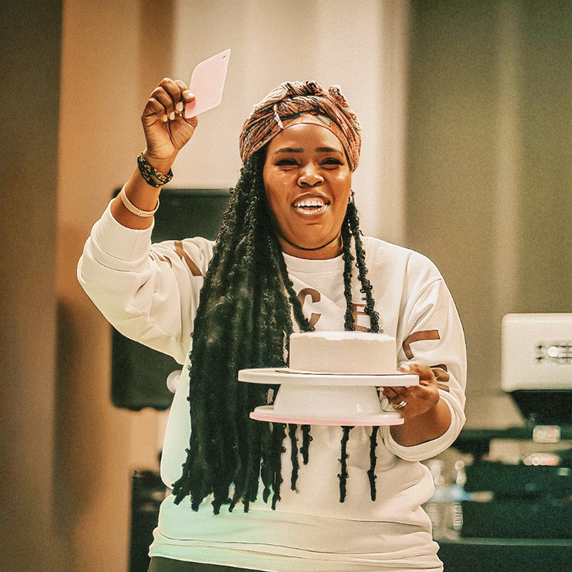 Woman holding a small cake and a card in a room with neutral decor