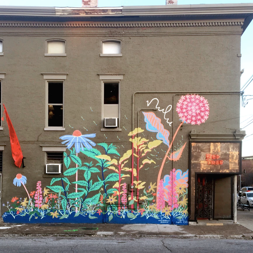 Vibrant, colorful Wildflower Mural on the side of a green building. This mural is featured on the Nulu Woman-Owned Walking Tour and in the Woman-Owned Directory hosted by Woman-Owned Wallet.