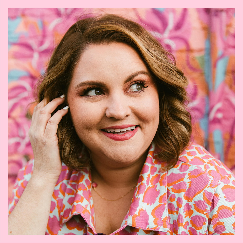 Woman-Owned Wallet, founder and CEO Amanda Dare wearing a colorful leopard print jumpsuit in front of a colorful floral mural