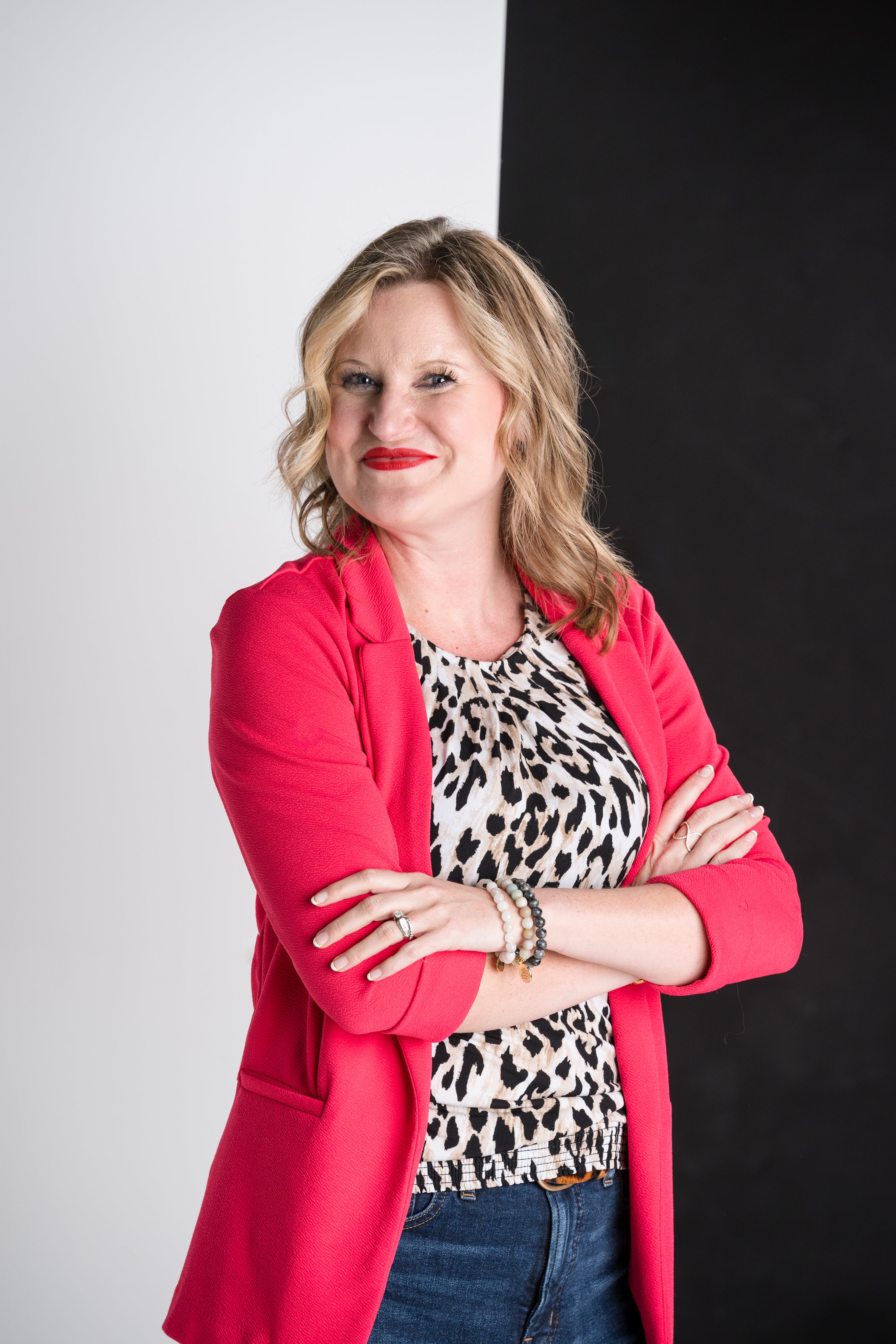 Woman wearing a red jacket and leopard print top against a black background