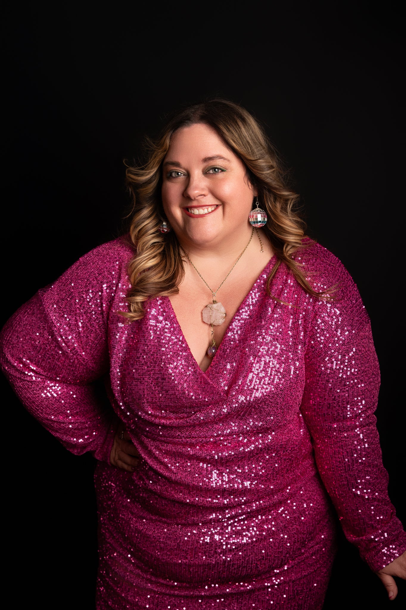 Woman wearing a pink sequin dress against a black background