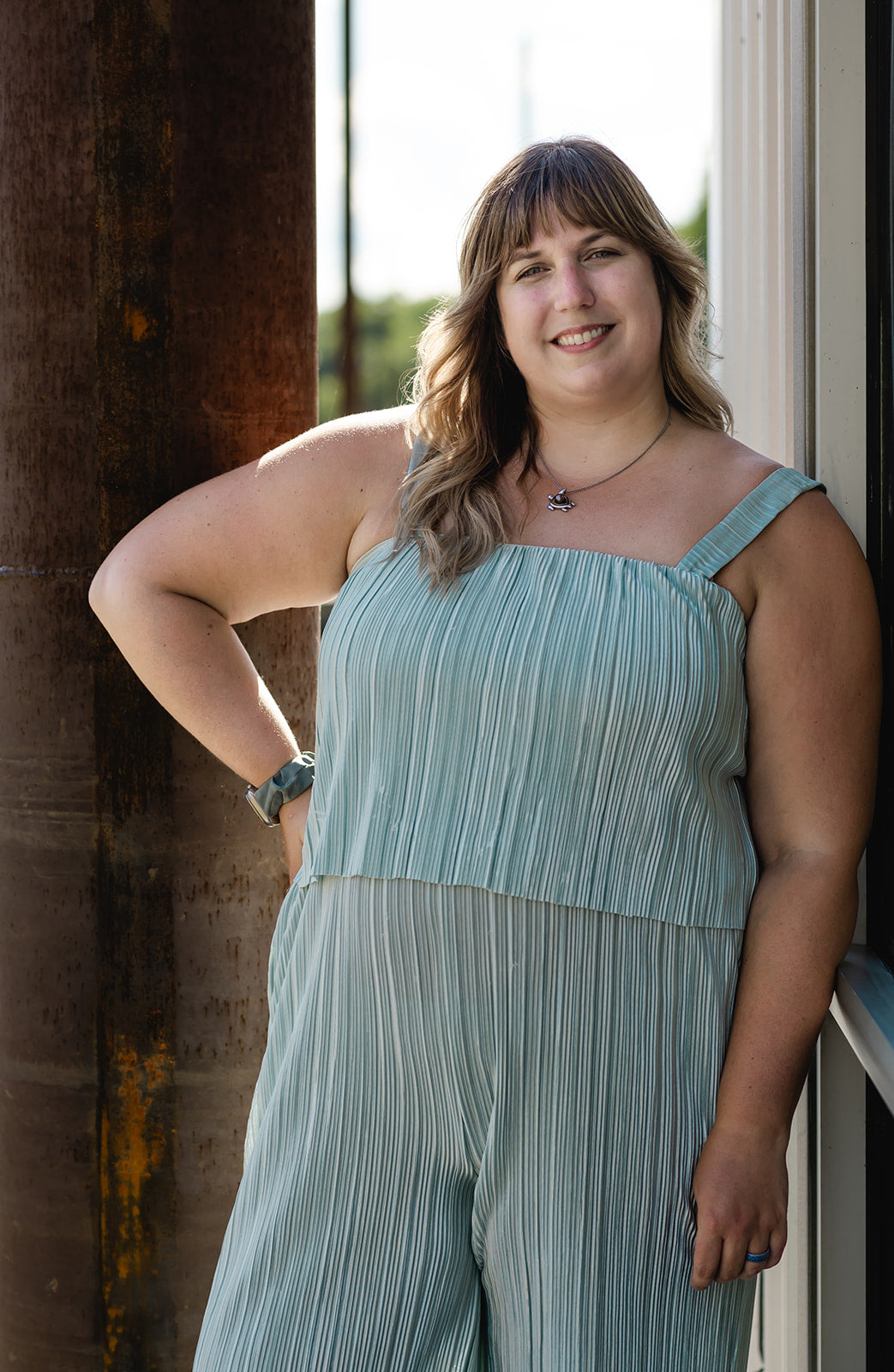 Woman wearing a light blue striped jumpsuit standing against a textured wall.