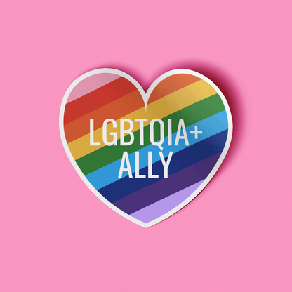 Heart shaped sticker that features the words &quot;LGBTQIA+ Ally&quot; in white text on top of a rainbow striped background. 