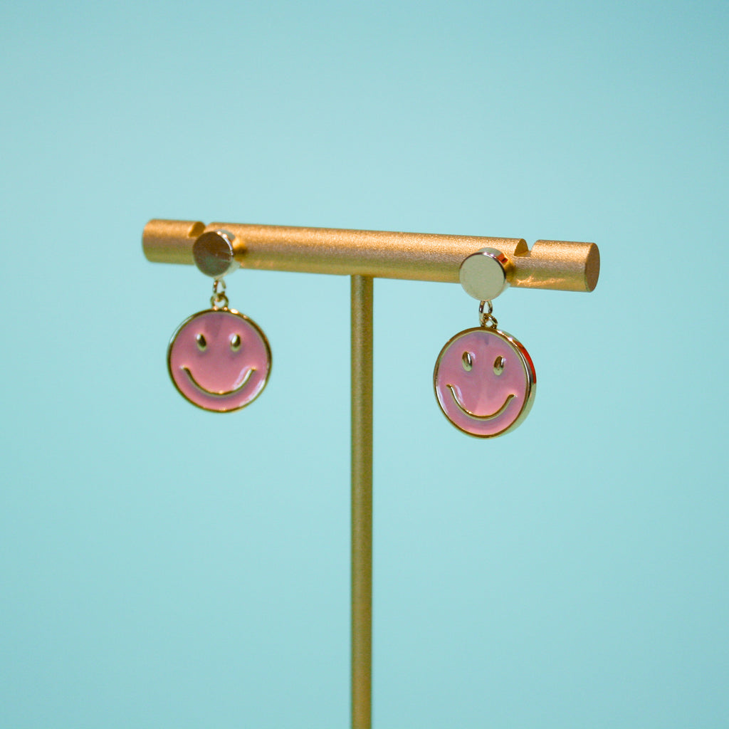 product photo of Be Happy earrings on a gold holder against a turquoise background