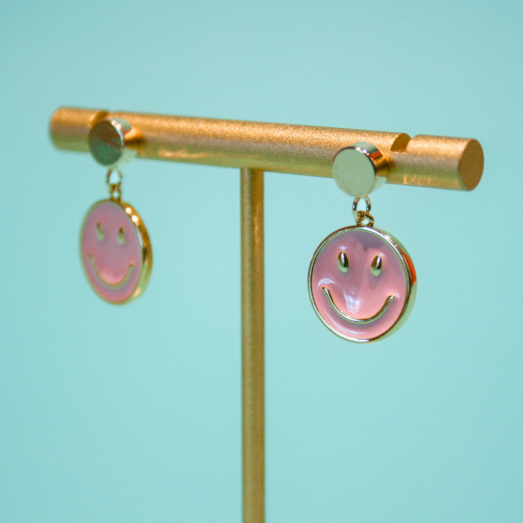product photo of Be Happy earrings on a gold holder against a turquoise background