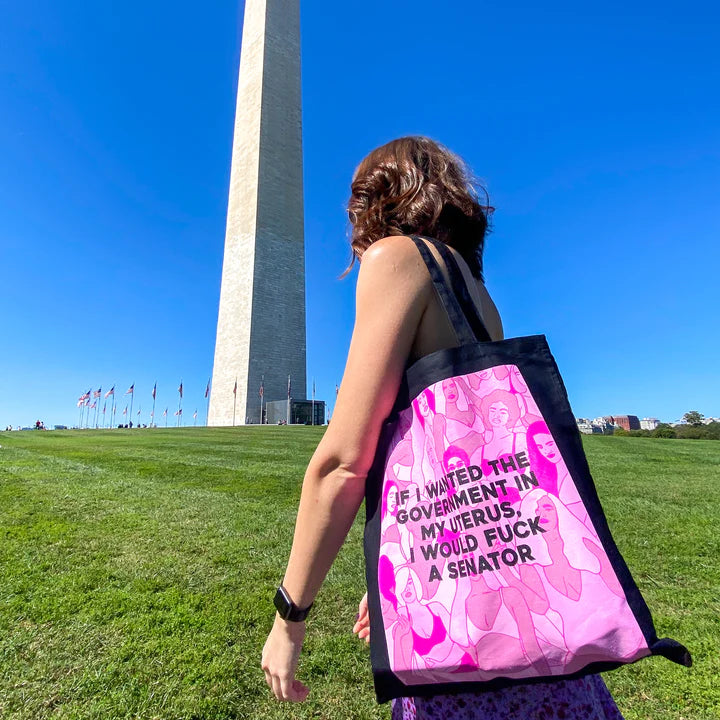 woman carrying the Fuck A Senator tote with a national monument in the background