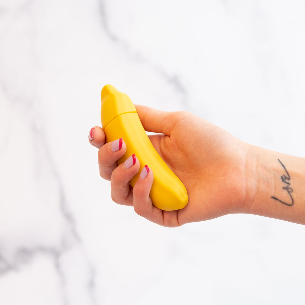 vibrator shaped like a banana held by a hand with love written on it in front of a white background