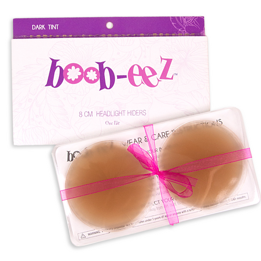 Package of nipple covers from the brand Boob-eez. Also shows the inner packaging including a plastic container that hold the silicone nipple covers in the color dark.