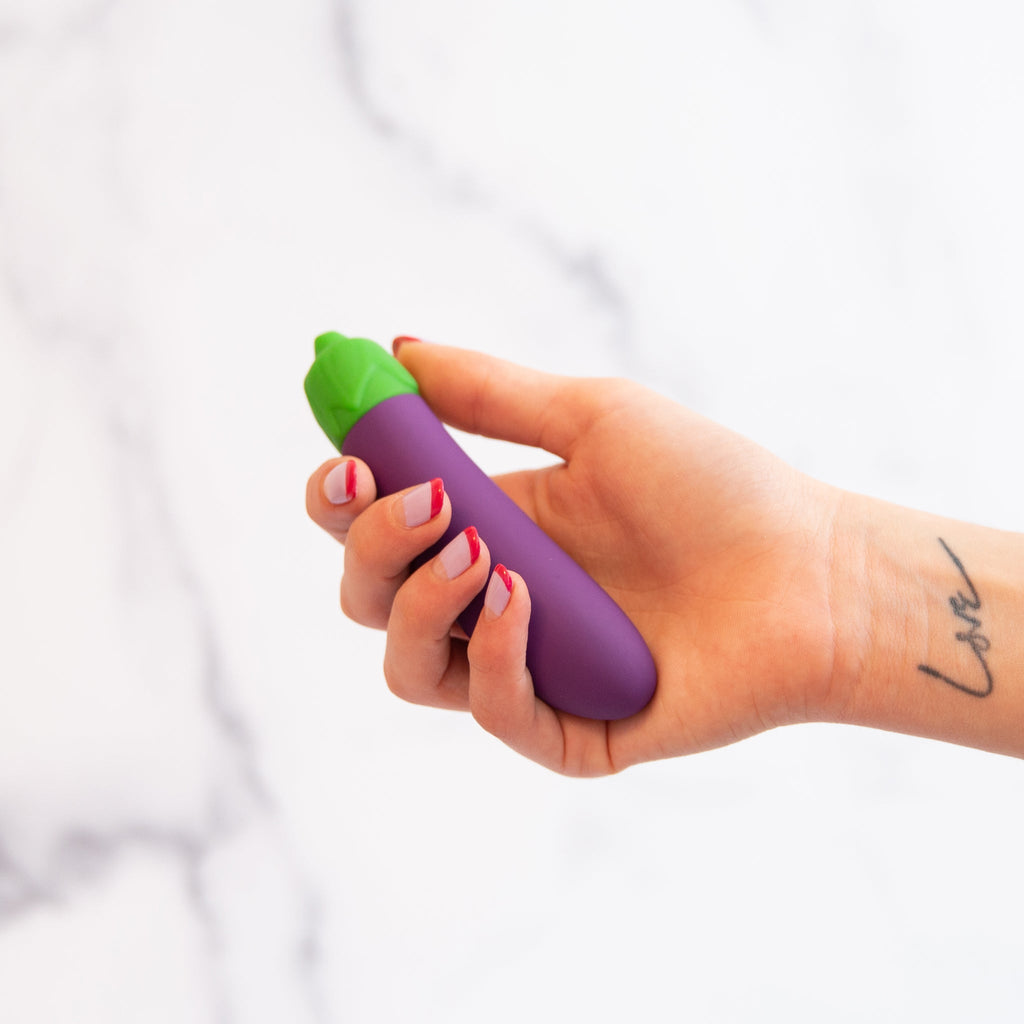 vibrator shpaed like an eggplant held in a hand with a tattoo that says love on a white background