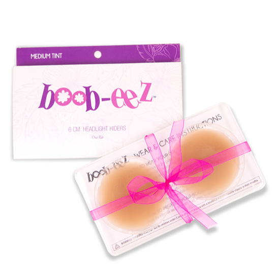 Package of nipple covers from the brand Boob-eez. Also shows the inner packaging including a plastic container that hold the silicone nipple covers in the color medium.